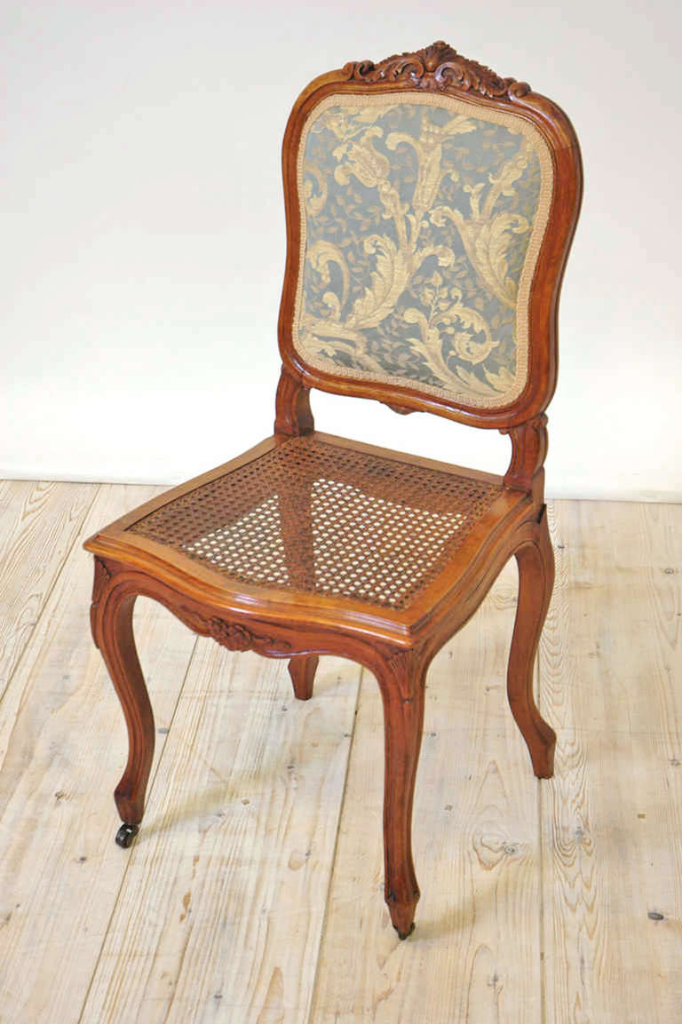 Set of six French 19th century Louis XV dining chairs with cane seats and upholstered backs.
Louis XV style dining chairs in walnut with well-articulated foliate carvings on backrest and apron, with woven cane seat and upholstered back in jacquard