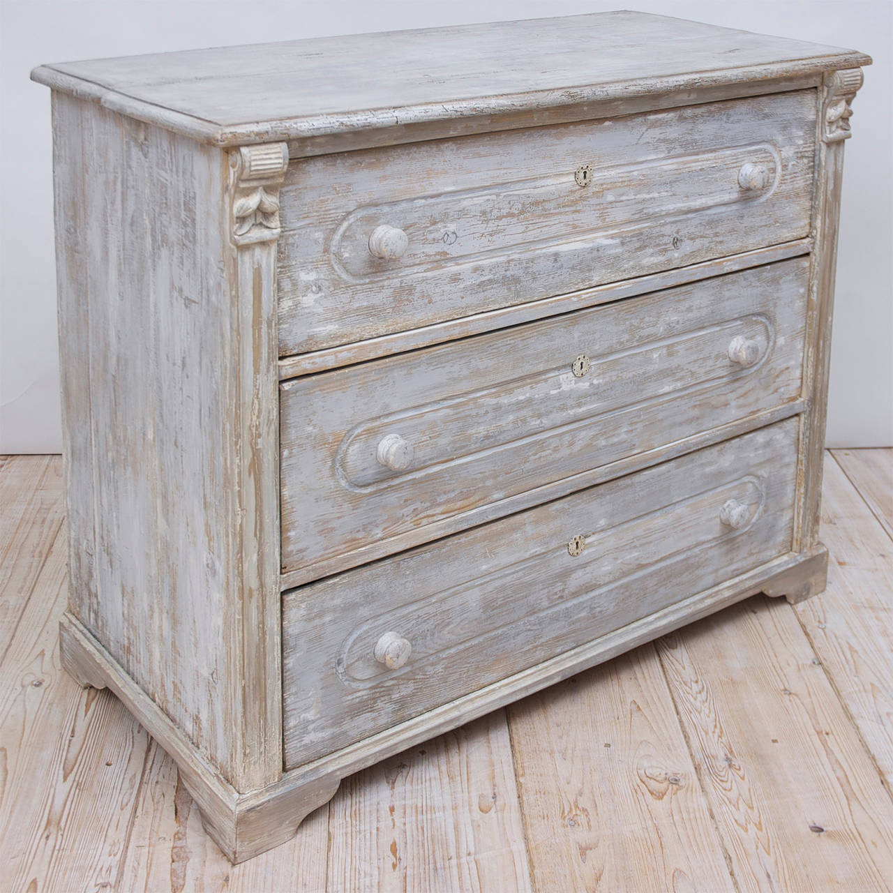 From the Austria-Hungarian Empire, a painted country chest with three large drawers flanked on the corners by a fluted molding capped with carved acorns. Offers original locks. Wooden pulls and bracket feet were added at some point in its history.