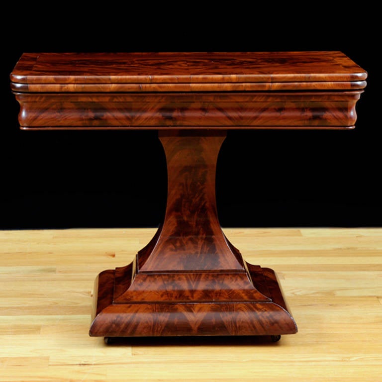 A very handsome Empire card or tea table in the Grecian style with center pedestal in mahogany and bookmatched figured mahogany, Boston, circa 1825. Offers hinged-top that pivots and opens to square. French-polished.

Measures: 36