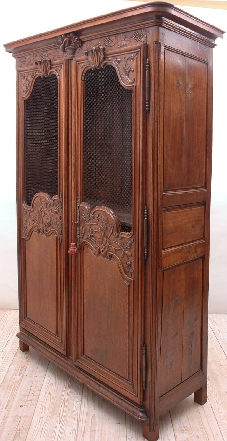 A beautiful French dower or wedding armoire in oak from Caen in Normandy. Offers well-articulated carvings of basket and rinceau of grapes and grape leaves on frieze, with scallops, roses, foliage and more grapes embellishing doors. This mortise and
