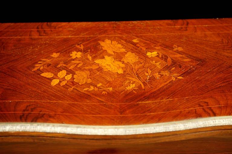 An exquisite game table in rosewood with fine floral inlays in various woods over the parquetry top. With bronze doré ormolu mounts on knees of cabriole legs, border of top & sabots on the front two feet. Line inlays embellish the sculpted,