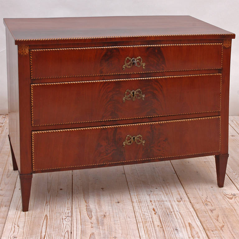 A unique Empire commode in mahogany with book matched, figured mahogany drawer fronts and top, satinwood bandings and inlays, with three drawers resting on tapered feet. Possibly from the Danish West Indies, circa 1820.

Measures: 41