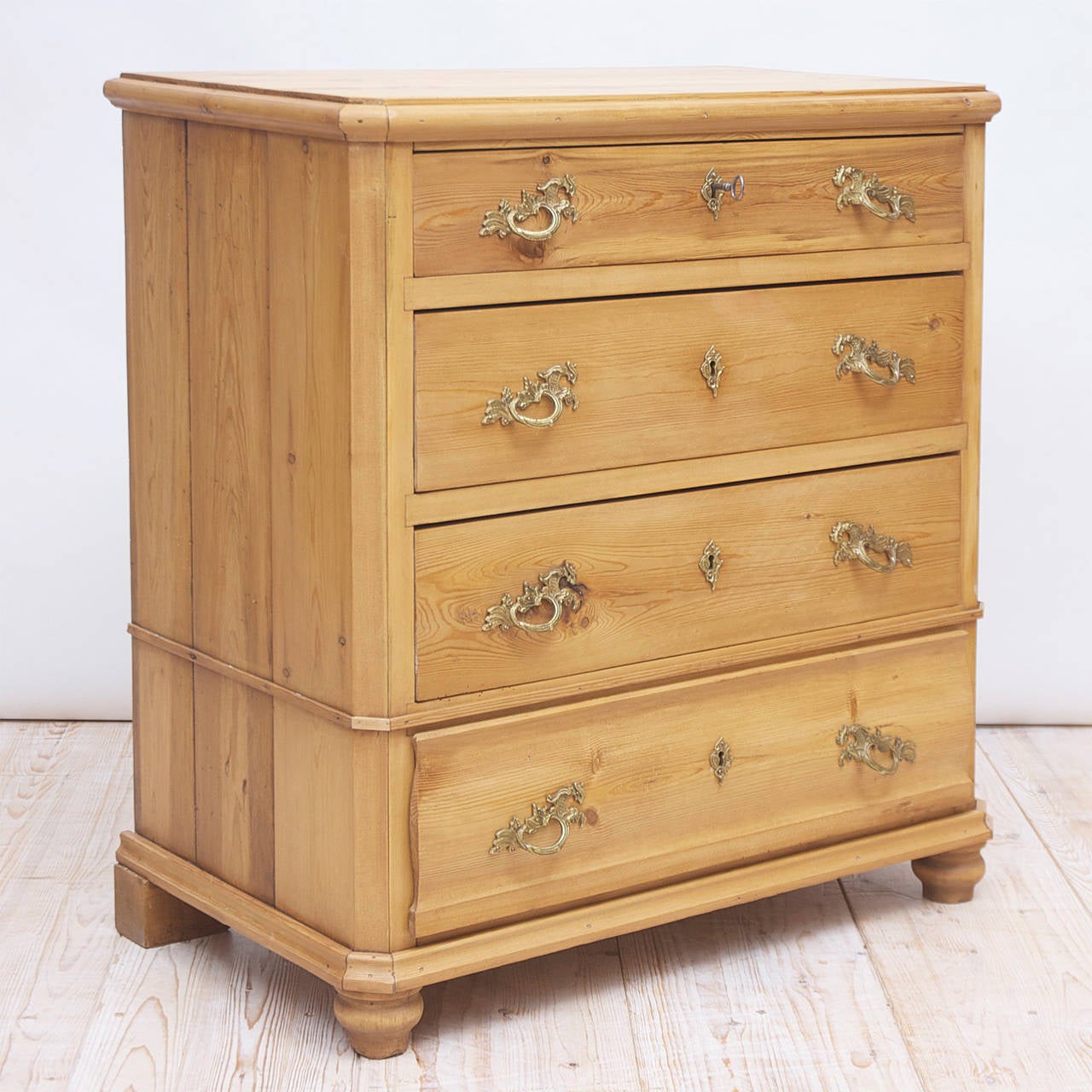 A chest with four drawers in pine with bronze doré pulls and keyplates and resting on turned feet, Sweden, circa 1850. Offers working locks and one key.
All of our pine can be painted upon request.

measures: 35 1/2" wide x 19 1/4"