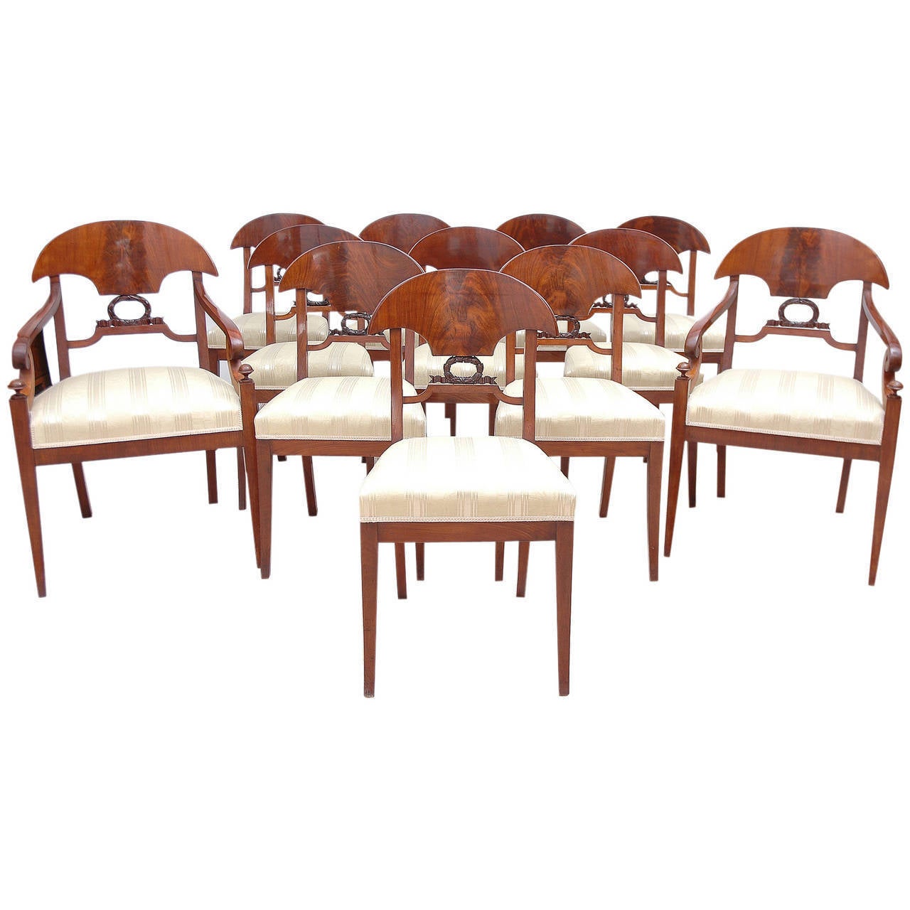 Original set of 12 Empire mahogany dining chairs from the reign of Karl Johan Sweden. Openwork back with carved decoration in the shape of a laurel. Set consisting of ten side chairs and two armchairs. Textiles and upholstery from the