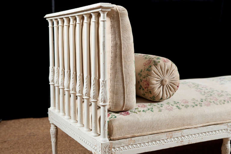 Very charming Swedish Gustavian style banquette in turned and carved wood. Features old hand-painted seat cushions, three back cushions and two bolsters.

Banquet can go up against the wall or float in the room. It has three back cushions with the