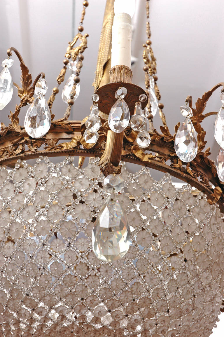 An outstanding Belle Époque ten-light chandelier featuring a crystal beaded basket assembled with flowers and beads in a pattern used by Baccarat.
The cast bronze armature of this chandelier is identical to an armature used by Baccarat in the