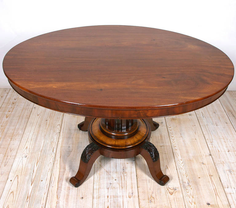 An oval table of exceptional design and quality with fluted pedestal column and well-articulated carvings of acanthus leaves on knees of each of four scrolled feet. The mahogany employed is an excellent tight-grained, West Indies species known