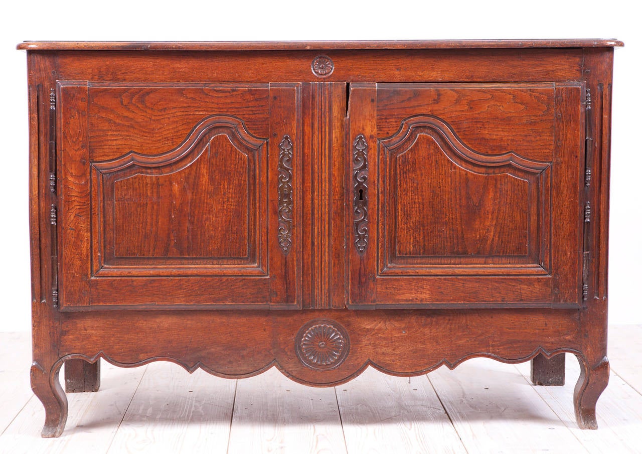 A French Louis XV buffet from Normandy in oak with hand-pegged and mortise and tenon construction, and with original rich patina. Base rests on carved apron with cabriole feet. Two doors feature raised curvi-linear panels,
France, circa 1770.
Note: