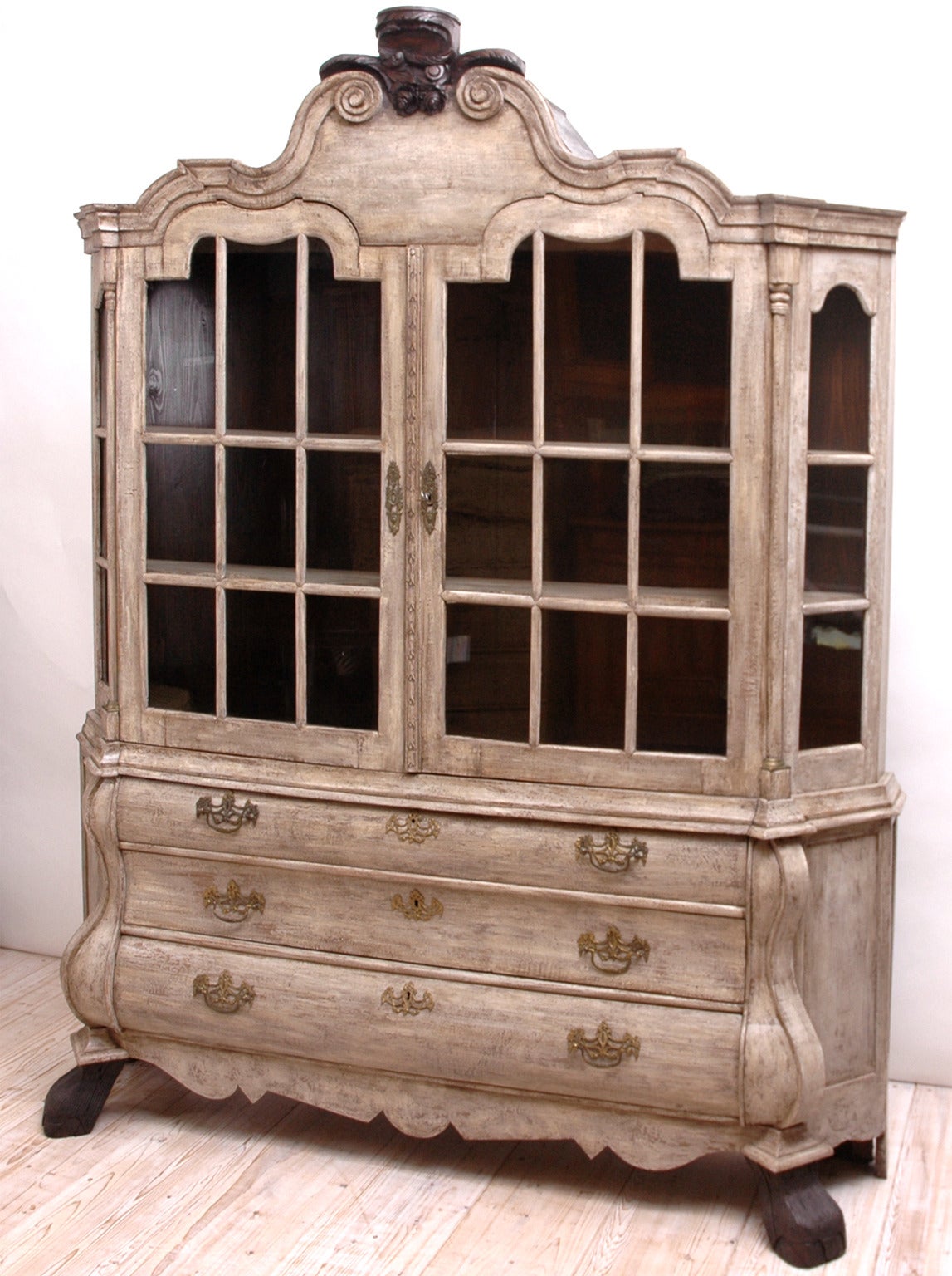 A lovely 18th century cupboard with bombe drawers, original glass, hairy paw feet and a carved floral bonnet. This beautiful vitrine is in oak with a more recent painted grey finish, reminiscent of the Swedish Gustavian Style.

Measures: 76