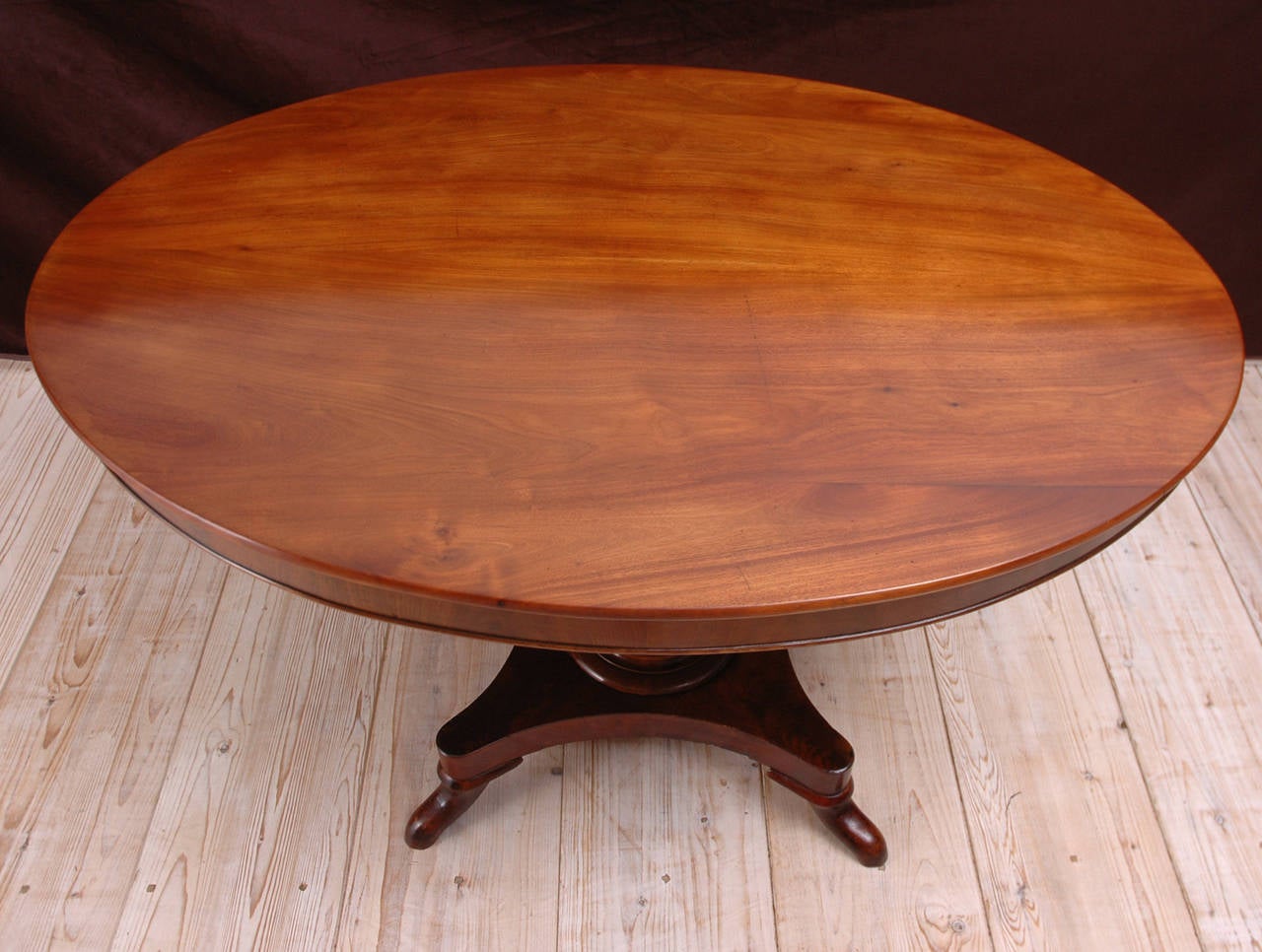 Center Table in mahogany with oval top resting on turned baluster-pedestal over quatre-form base, Denmark, c. 1840. This type of table typically accompanied a salon including a sofa, side chairs and arm chairs and would have been used in front of