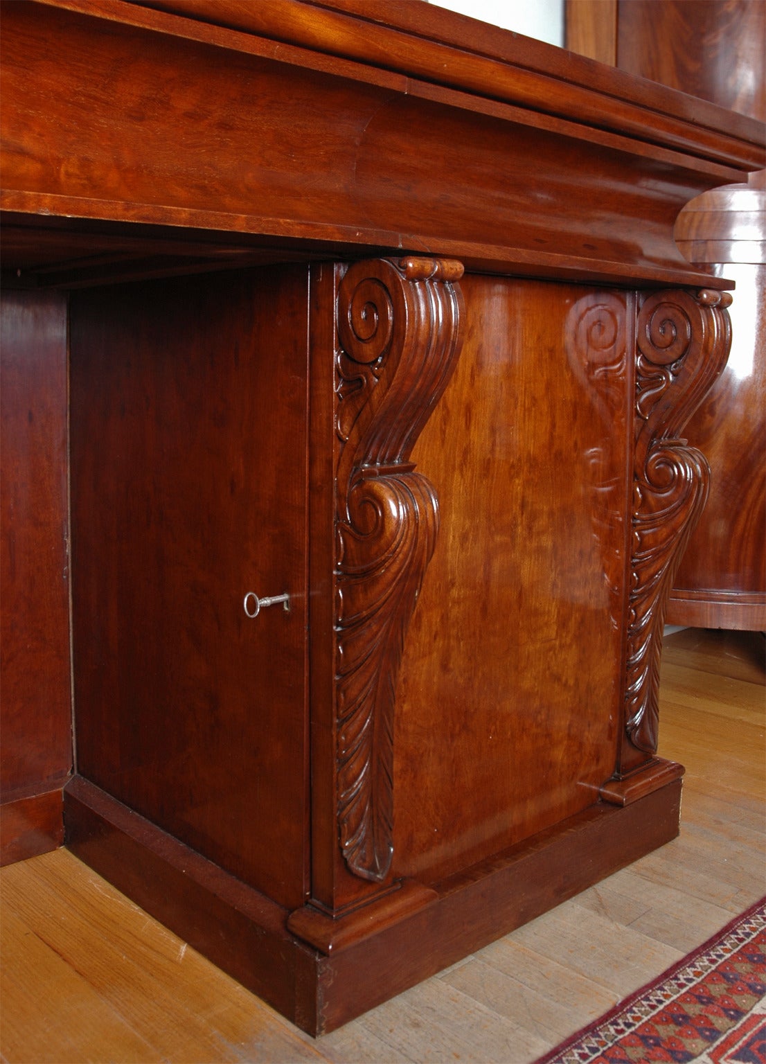 A very fine and unusually long Charles X sideboard with beautifully carved volutes decorated with acanthus leaves flanking each of two cabinet doors, below three concave drawers. Back-splash is embellished with carved crown of laurel leaves. Solid