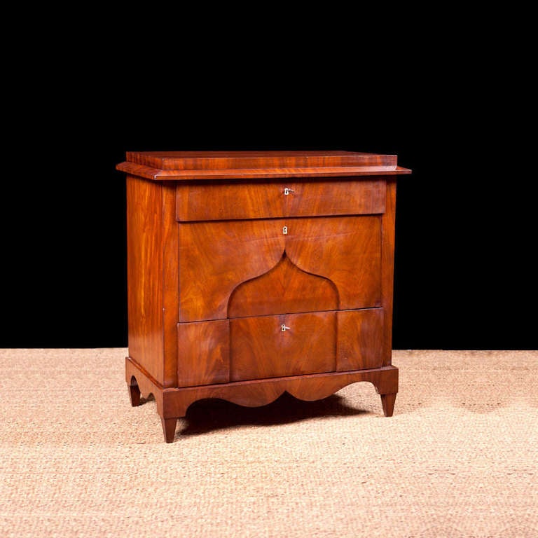A lovely Biedermeier chest in book-matched Cuban mahogany with pedestal top, three drawers with ivory keyholes, and a plinth base with tapered feet. Northern Europe, circa 1820. This small commode would make a lovely foyer or entrance table,