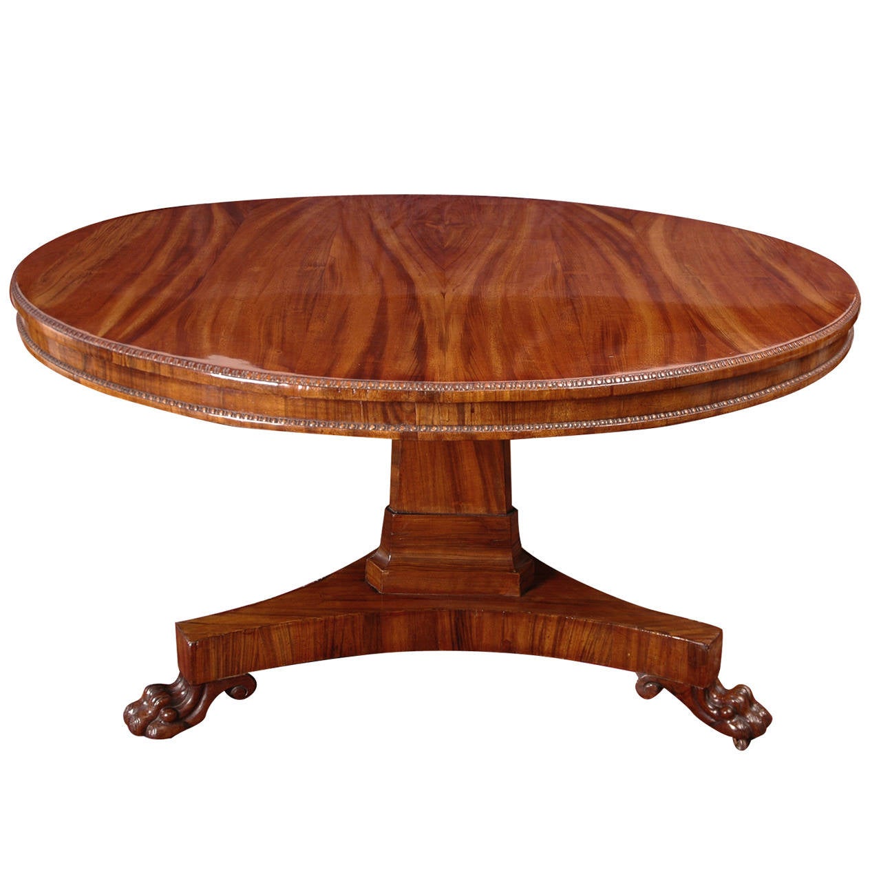 An exceptional English Regency tigerwood table with round top over tripod base with carved lions' paw feet. Offers an ideal neoclassical center hall table or intimate dining or breakfast table. The tripod base makes it easier to assemble chairs