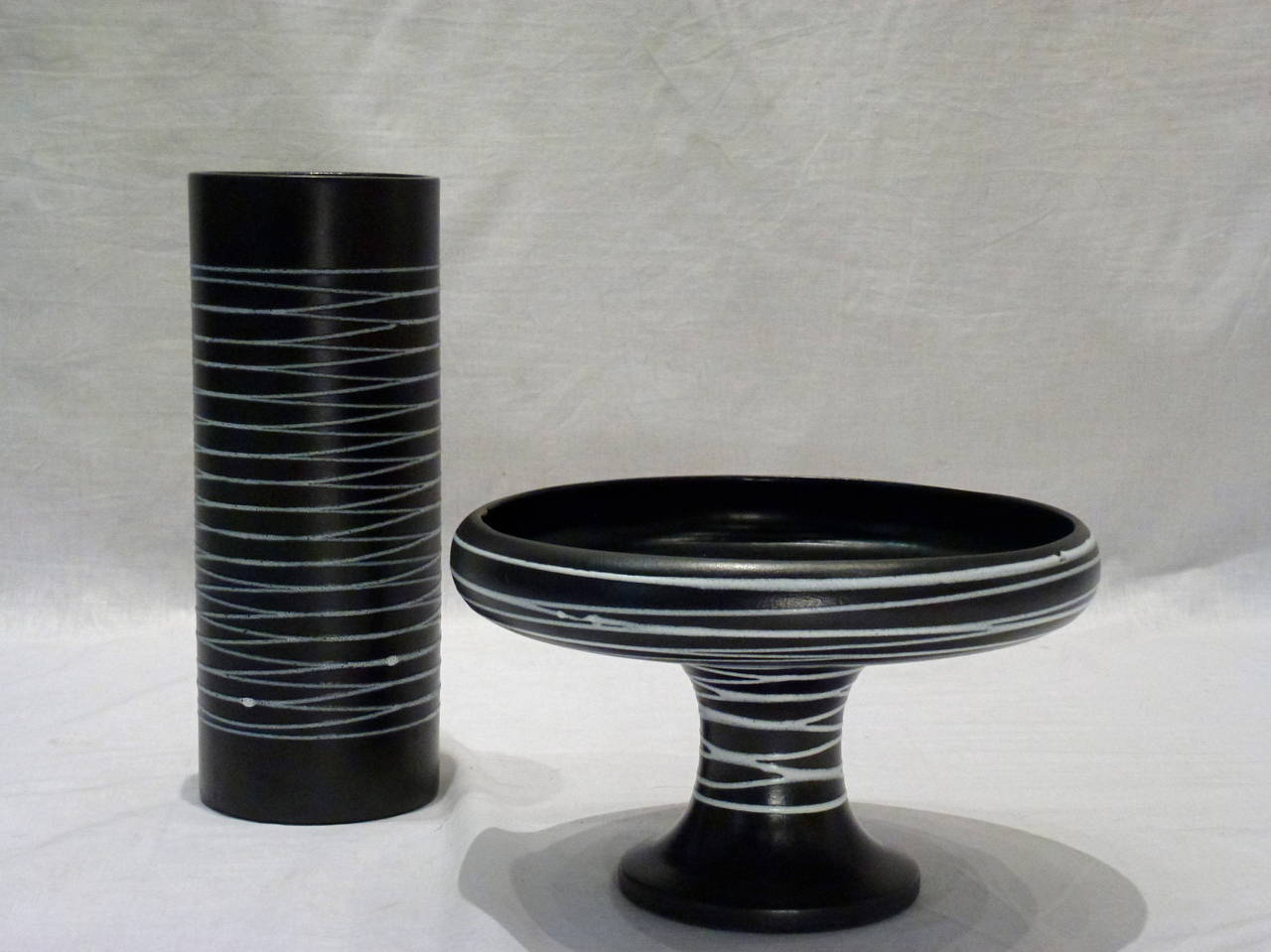 Beautiful vintage set of two black pottery pieces with white crisscross line detailing by Royal Haegar set consists of a cylinder vase and compote.

Vase: 4.75
