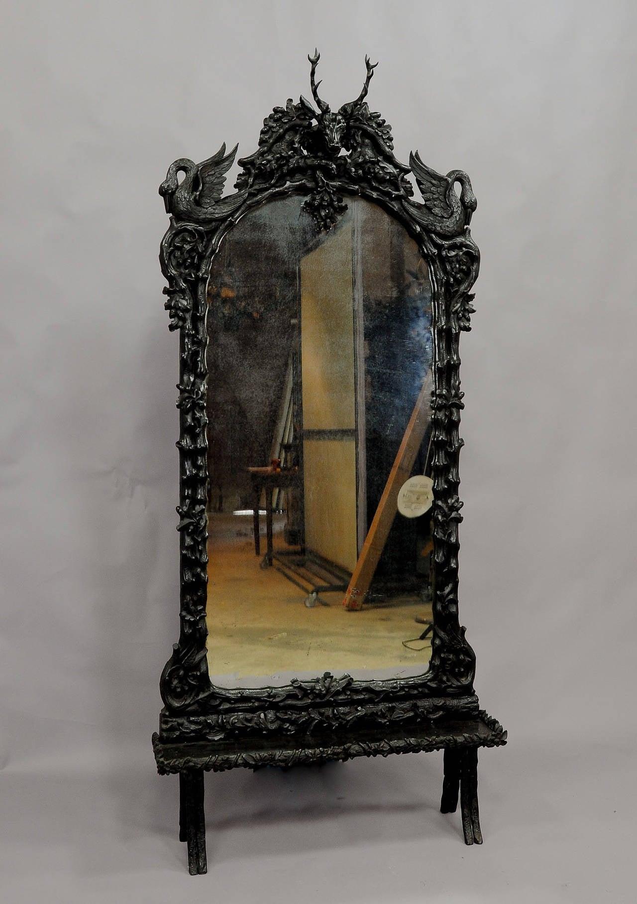 an extensive carved wooden hall mirror with console. entirely decorated with fine carved branches, oak leaves, a stag head on top and left and right a swan. executed ca. 1890 in Germany, painted in black, with antique mirror.
