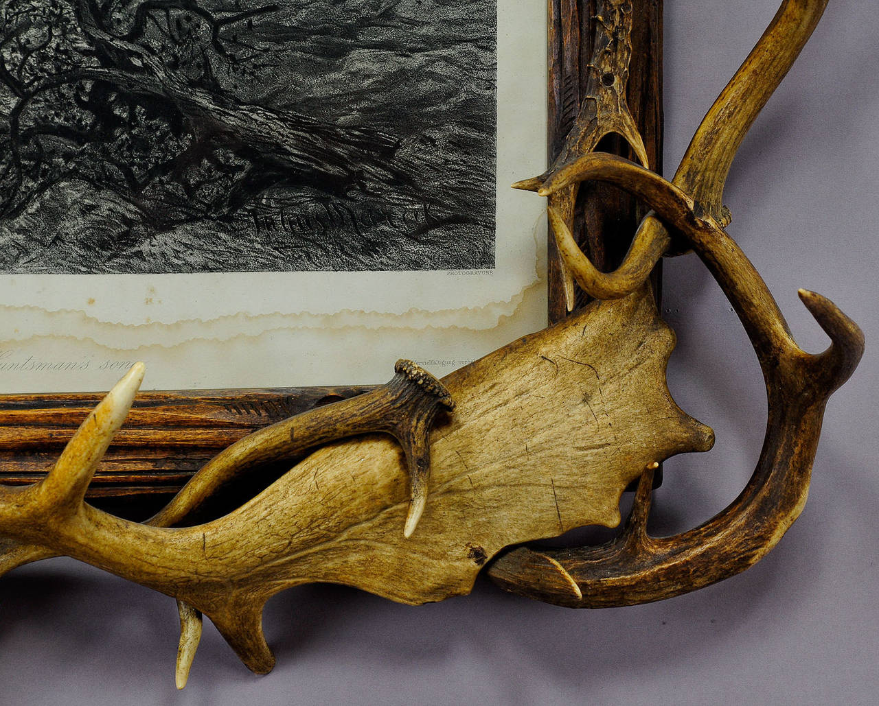 a large antique black forest antler picture frame. a carved wood frame decorated with antlers from the deer, virginia deer, fallow deer, carved and turned horn roses. print with the name 