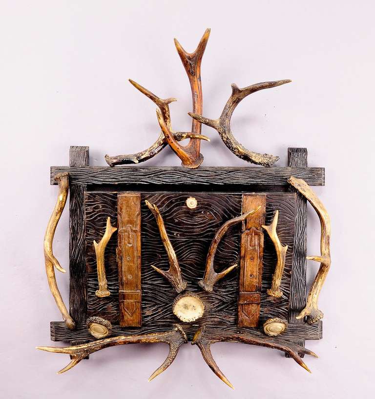 a wall newspaper rack made of carved wood, decorated with several antlers and turned horn roses. germany ca. 1880.