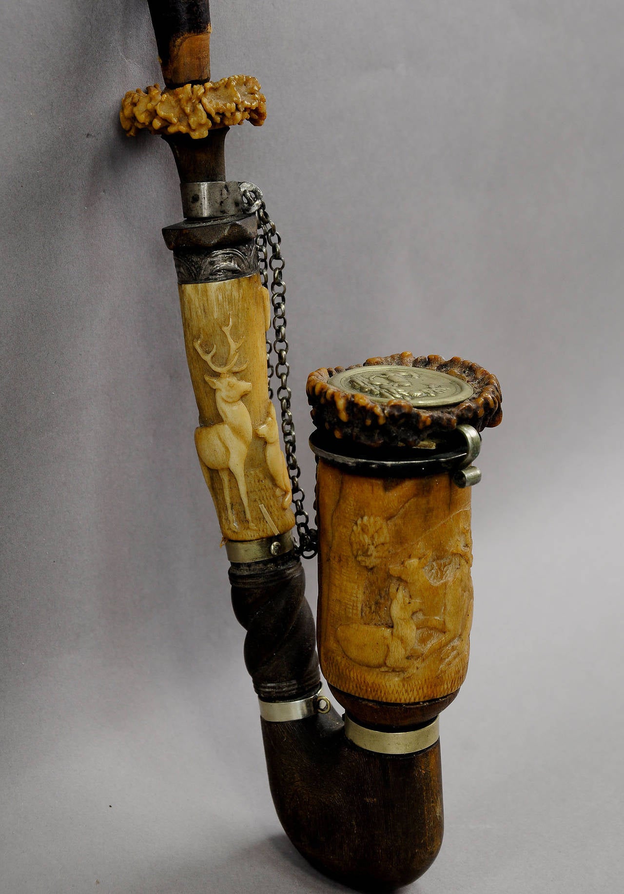 A wonderful antique tobacco pipe. Made of wood, horn roses and carved horn in high relief. the carving shows stags and roe deers. metalworking joints, one with hunting ornaments. A turned horn end as lid, decorated with a metal badge with deers in