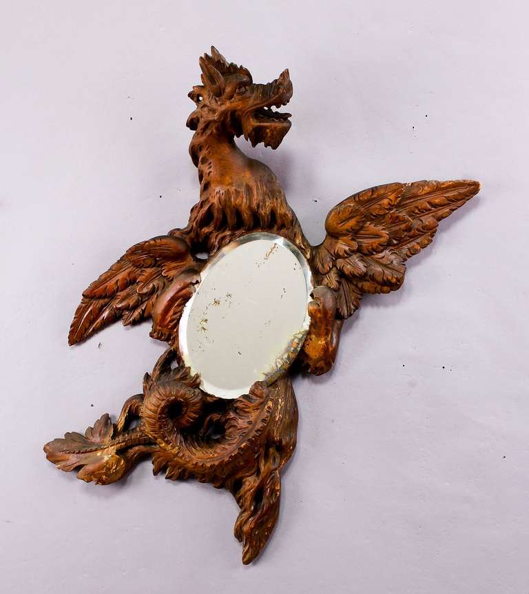 an antique wooden carved mirror in the shape of a dragon, executed circa 1900.