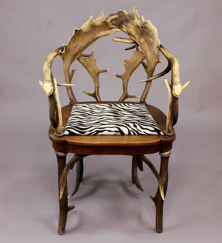 an antique black forest antler armchair, made of horns from the deer and fallow deer.  decorated with a carved horn rose. executed ca. 1900.