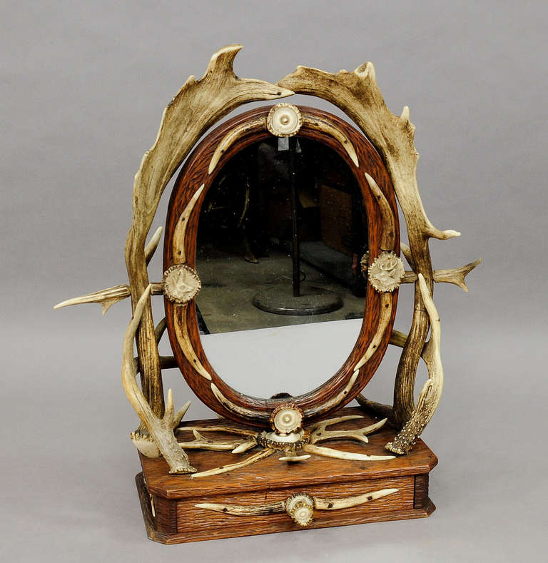 a wonderful antique antler vanity mirror. carved wood decorated with antlers from the deer and fallow deer and turned horn ends. with one drawer, movable oval mirror. executed ca. 1880.