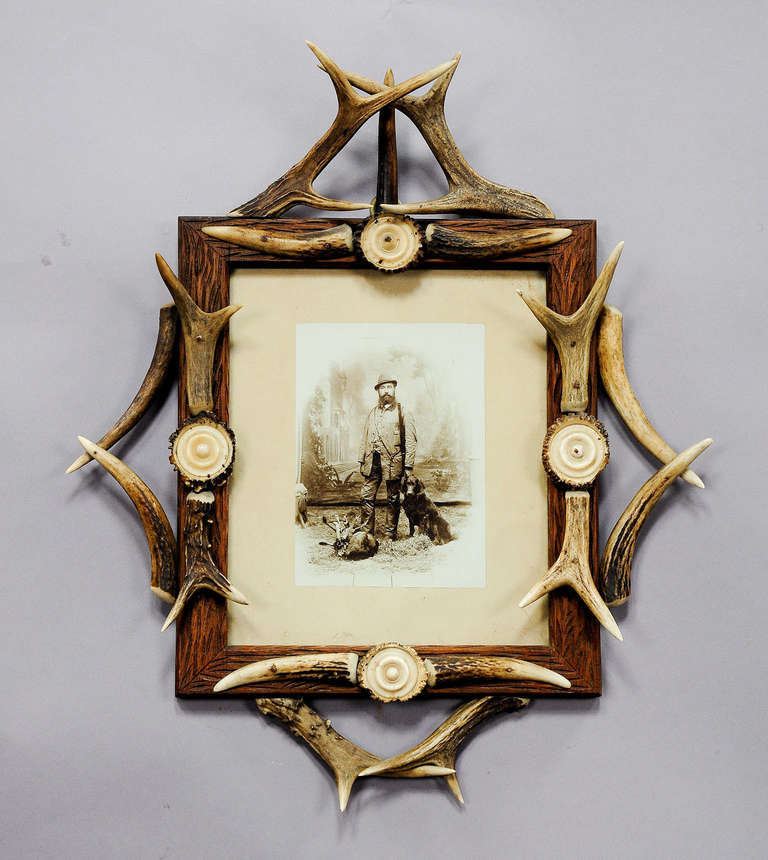 Cadre en forêt noire avec bois de cerf et photo ancienne d'un chasseur avec du gibier