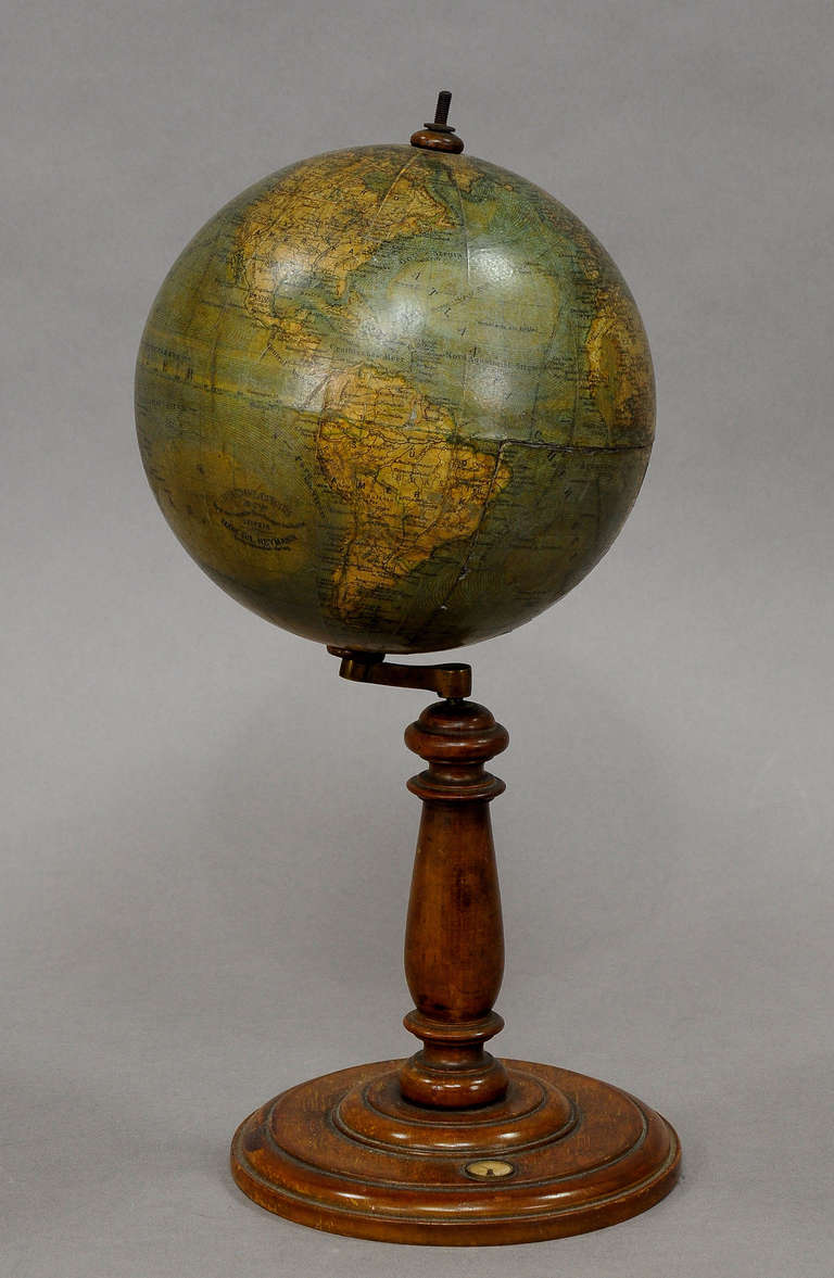 a small earth globe by ludwig julius heymann, berlin ca. 1890. 12 printed segments on a cardboard bowl. revolvable mounted on a turned wooden base with compass. perimeter 37.8