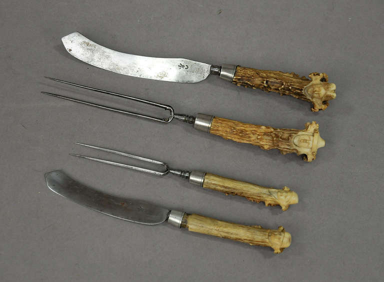 4-part serving cutlery, 2 knifes and 2 forks, with antler handles. the ends carved as human heads. executed about 1700.