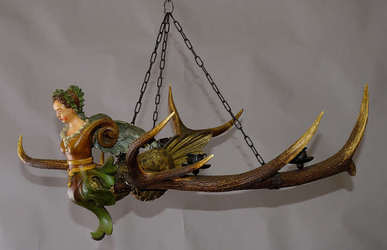 an antique antler chandelier with hand-carved and painted lady statue. Named 