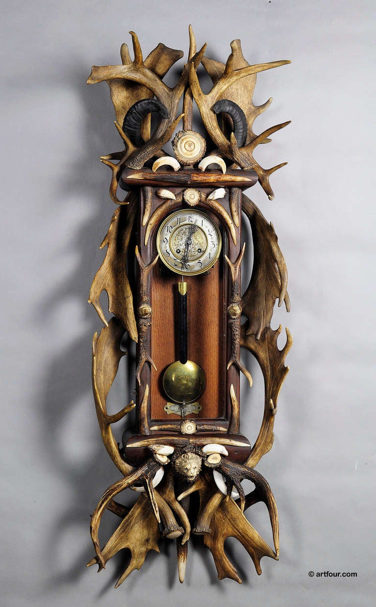 a rare and huge black forest wall clock. oakwood case richly decorated with antlers from the deer and fallow deer, wild boar tusks, mountain goat horns, carved horn roses. executed ca. 1900. the oak wood case is with glasses on three sides. it has