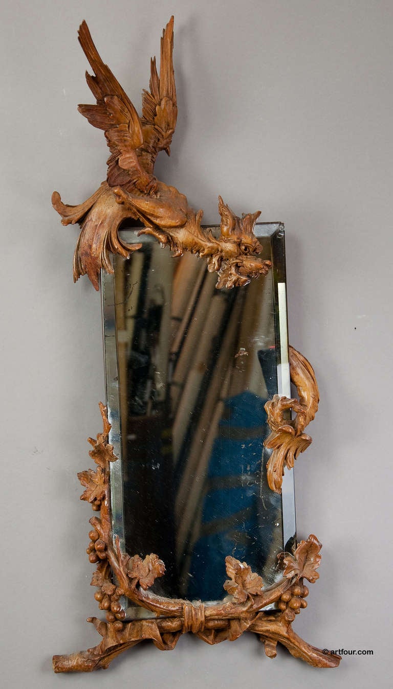 a wall mirror decorated with a carved wood dragon and vine tendrils. executed ca. 1900.