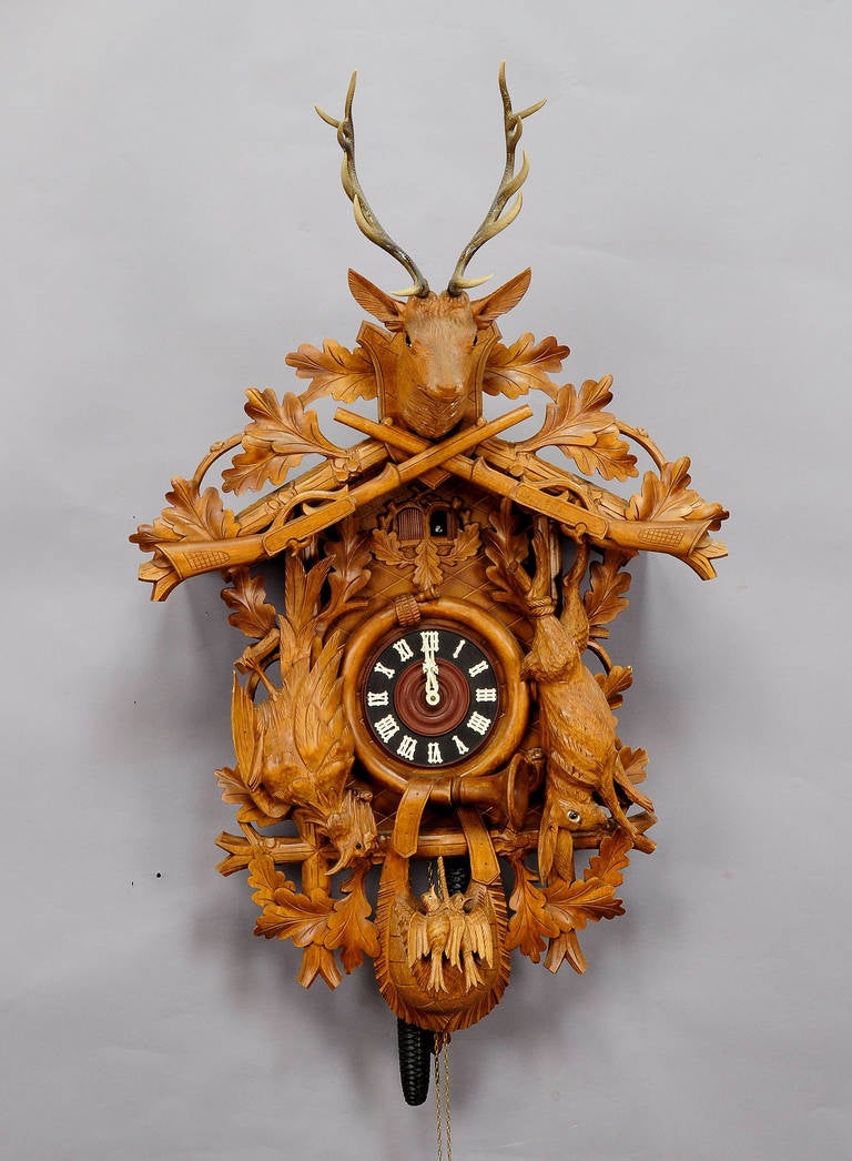 A large vintage Black Forest cuckoo clock with carved wood deer head, hare and partridge, battery operated musical play, Germany, circa 1950-1960. Working order. Antlers on top made of synthetic material.