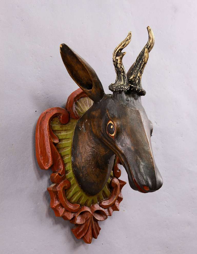 A hand-carved wooden roe deer head with abnormal antlers, mounted on a carved and painted wood plaque. Executed circa 1900.