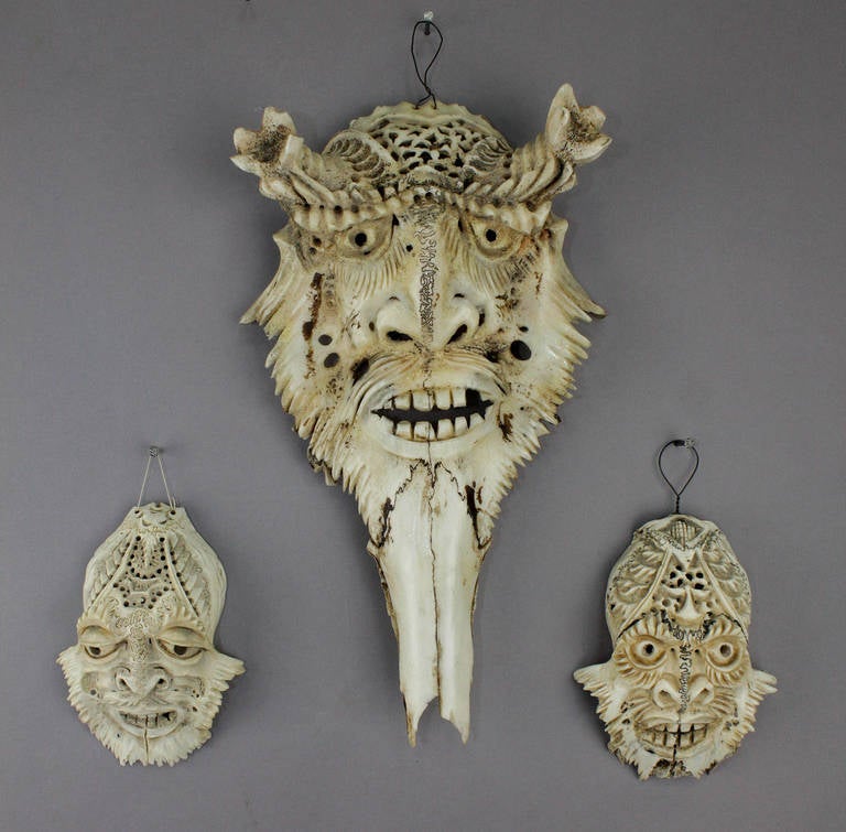 a set of three vintage handcarved deer skulls with elaborate carved fantasy faces, executed ca. 1950.