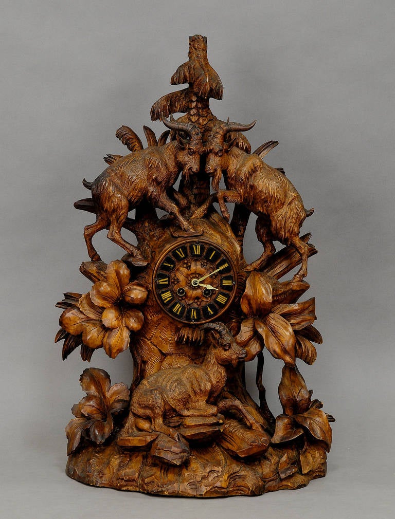 a handcarved wood mantle clock with two mountain goats standing on a rocky base and a third sitting on the base. a very detailed carving. clockwork overworked and cleaned by a clockmaker - working order. manufactured in brienz, switzerland ca. 1900.