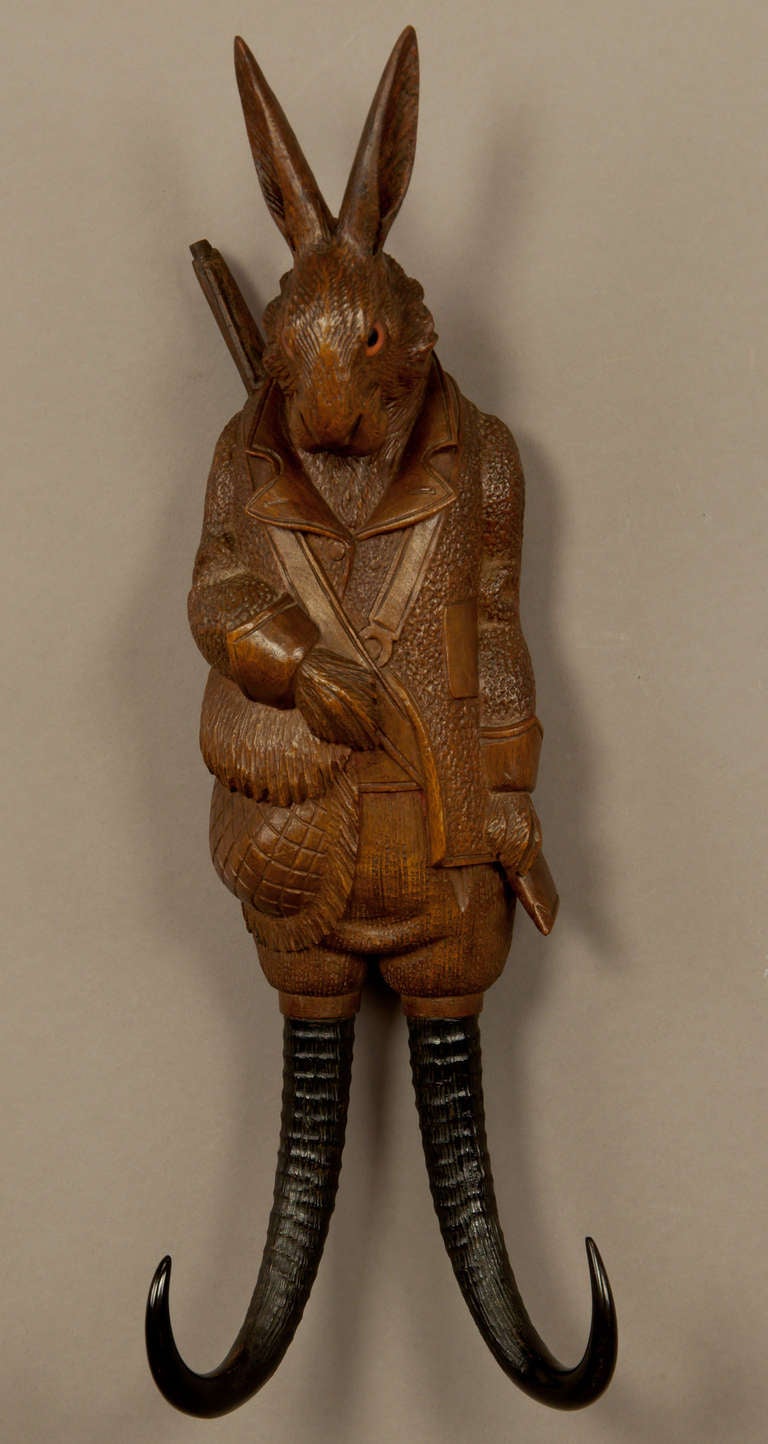 a whimsical handcarved hunting hare whip holder / coat hook. executed ca. 1900, swiss - brienz. with music work integrated in the body which starts playing when something is hanged on the chamois horns.
