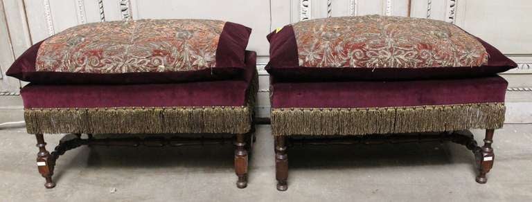 A pair of 17th century Spanish benches upholstered in plumb velvet with metallic embroidery design depicting flowers and leaves. A gold metallic fringe trims the benches. The frame and embroidered design are from the 17th century. The velvet is