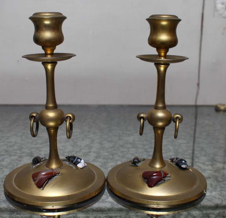 A pair of bronze candlesticks with carved mineral stone bugs on base.
