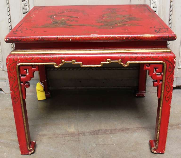 A French red lacquered chinoiserie table with gilt decoration. the surface is decorated with a figure and garden scene with stairs. This table is highly decorative and dates from the 1930s.
