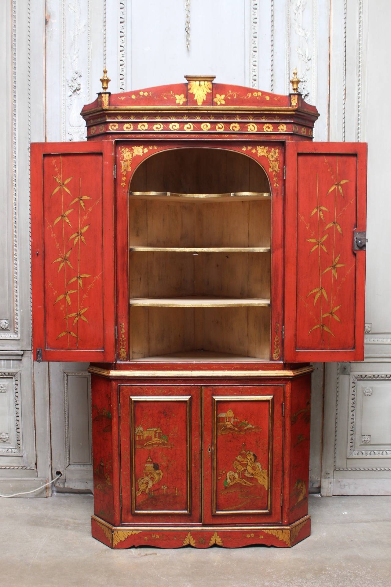 An English Georgian style red japanned and parcel-gilt corner cupboard. This pine corner cabinet is a 19th century piece with mid-20th century painted decoration.