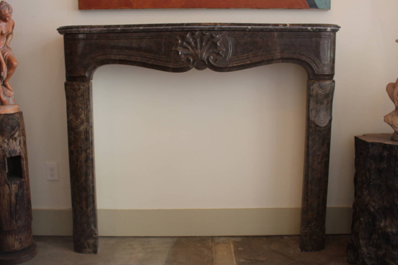 A large early 18th century French Regence carved brown marble mantelpiece with a large carved shell. This mantel is made from an extinct and very unusual marble. It is a great size and has wonderful proportion.