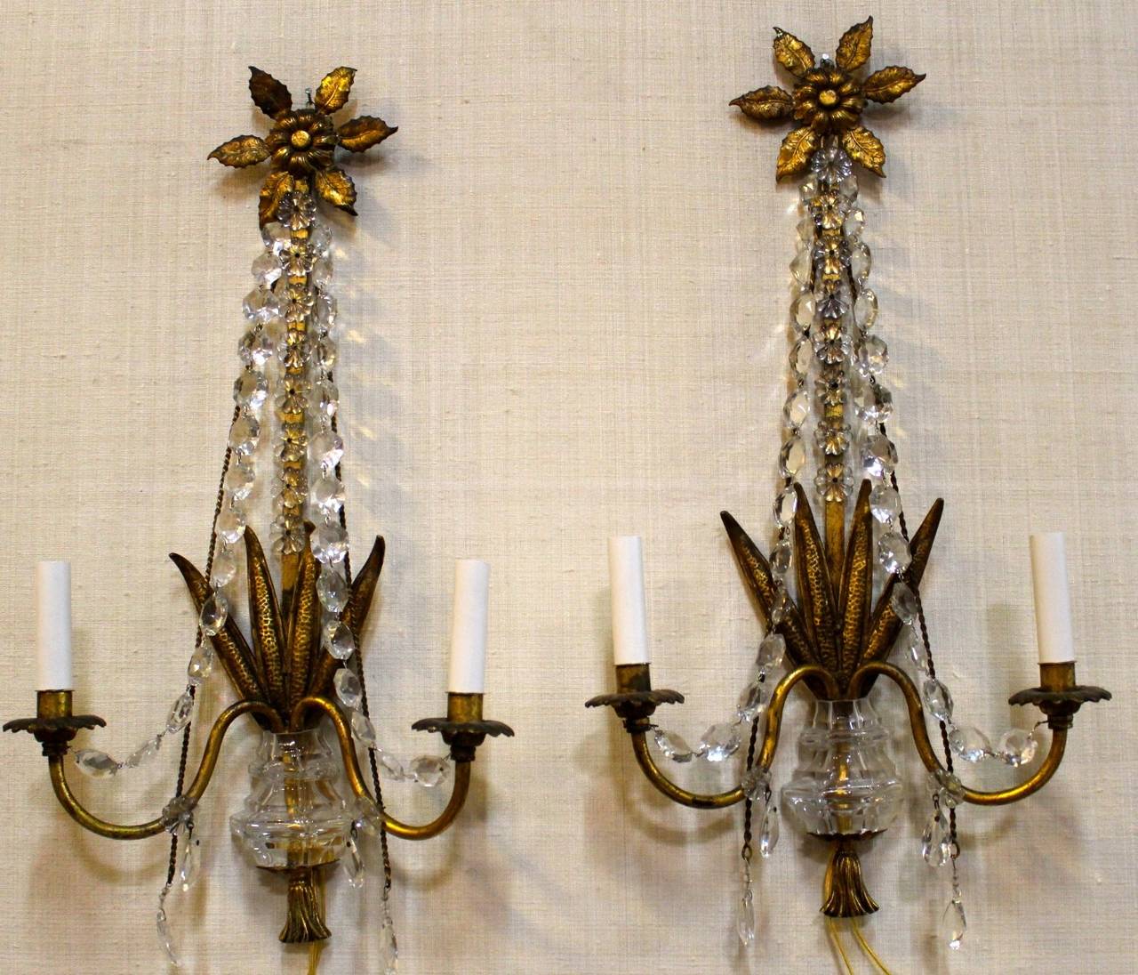 A Pair of gilded iron and crystal sconces.