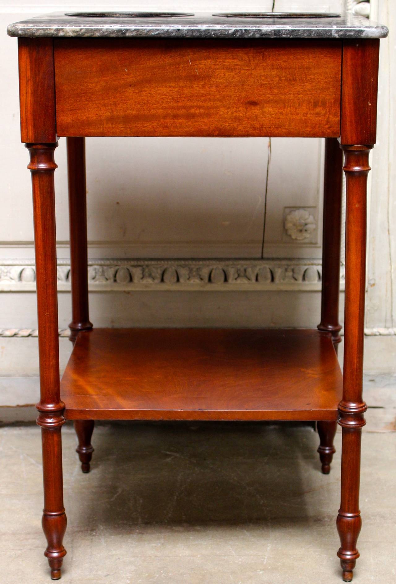 A French Directoire wine tasting table in mahogany with a gray marble top and brass inserts to hold wine bottles.  This table dates from the late 18th century and is still very functional today.  