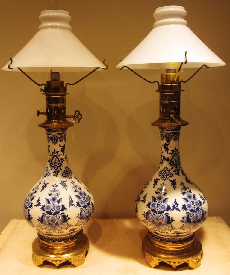 A pair of blue and white faience lamps with bronze mounts and milk glass shades. 
Measures: Overall: 10.50
