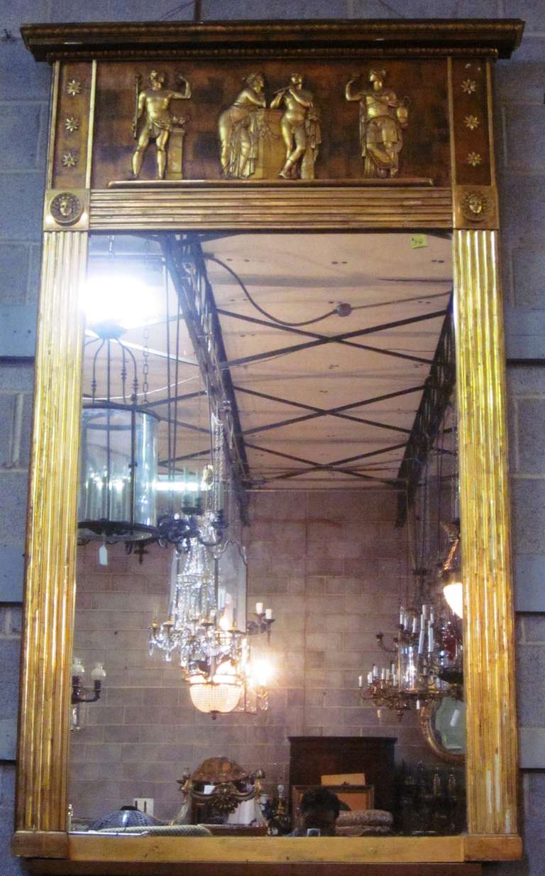 An Empire giltwood mirror with a fluted carved border and carved relief of classical figures.