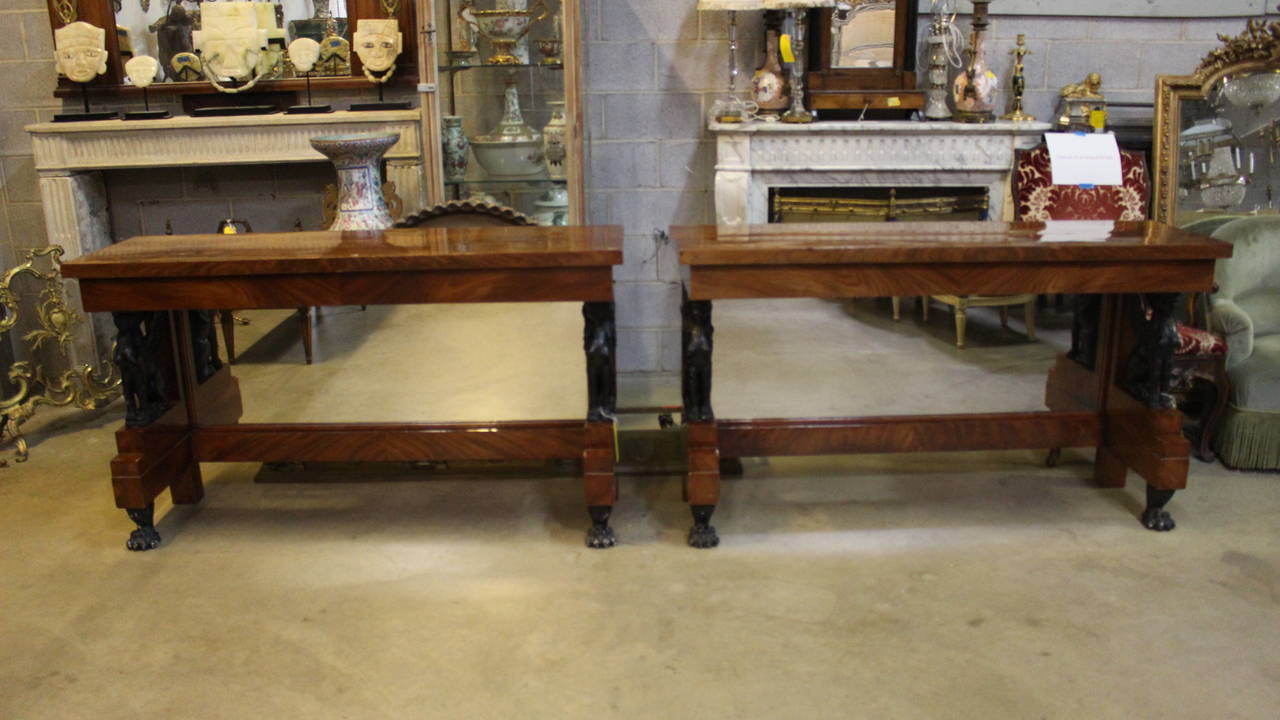 A Pair of French Charles X console tables in mahogany with ebonized sphyx and mirrored backs.