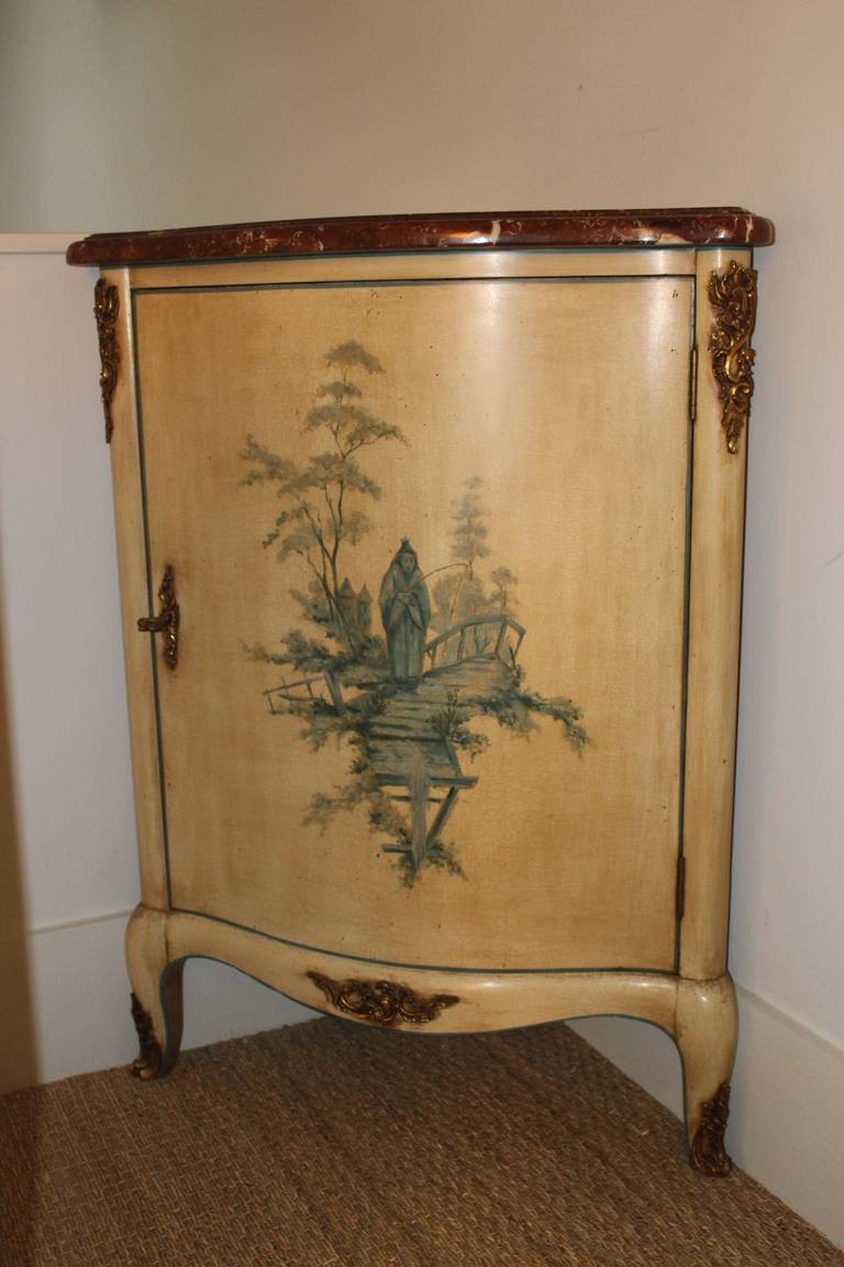 A Louis XV style corner cabinet with a painted finish, bronze mountings and a marble top.