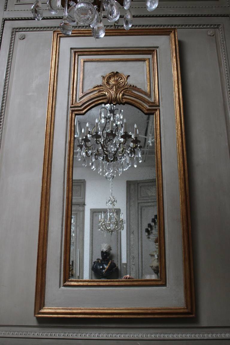 Pair of French Regence style mirrors with a painted gray and parcel-gilt finish.