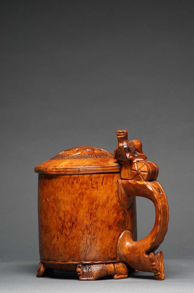 A fine and important Norwegian tankard in birch burl wood with carved lion motif on top of lid, thumb piece and feet. Beautiful color, ceremonial markings on inside, lovely metal strap repair on outside of base.