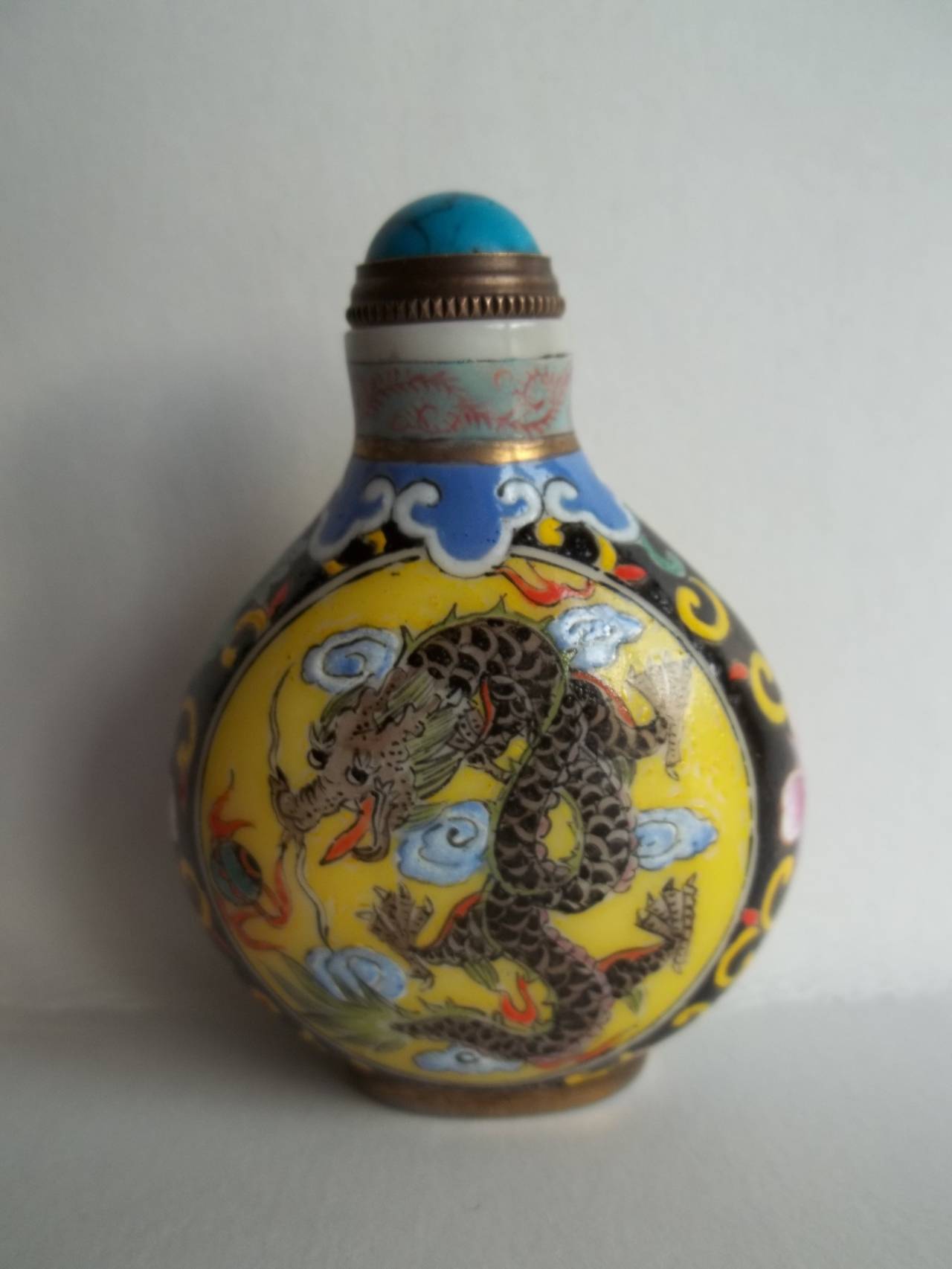 This is a very good example of a Chinese Snuff Bottle, made from opaque white glass with hand enamelled decoration.

The main decoration to one side is of a five toed (clawed) dragon chasing a flaming pearl on a yellow ground. To the reverse are a
